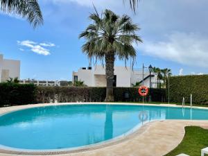 een zwembad met een palmboom op de achtergrond bij Lovely 3-bedroom townhouse with shared pool in Estepona