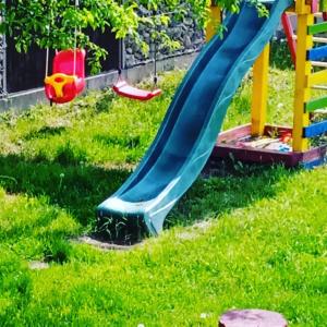 a slide on a playground in the grass at Pensiunea Gradinarilor cu ciubăr și stație de încărcare electrică auto in Comăneşti