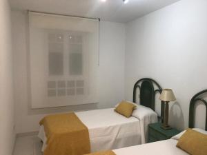 a white room with two beds and a window at Apartamento en La Toja de tres habitaciones in O Grove