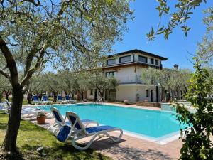 a swimming pool with two lounge chairs and a house at Residence Ulivi in Cavaion Veronese