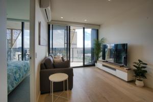 a living room with a bed and a tv and a couch at King Bed Luxury CBD Coastal Room with Amazing City Views, Spa, Gym, BBQ, Steam & Sauna Rooms in Adelaide