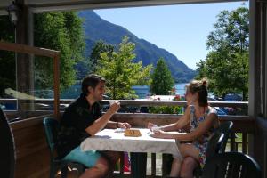 a man and woman sitting at a table on a porch at Camping Al Lago Ledro in Ledro