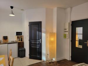 a room with a black door and a kitchen at Studio 1 du Temple Hyper Centre in Cambrai