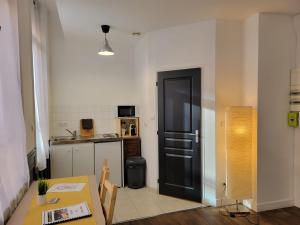 a kitchen with a table and a black door at Studio 1 du Temple Hyper Centre in Cambrai