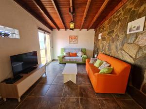 a living room with an orange couch and a television at Beach Villas 16 con piscina privada in Caleta De Fuste