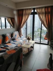 ein Wohnzimmer mit einem Sofa, einem Tisch und Fenstern in der Unterkunft 2BR Portovita Condominium North Tower in Manila