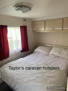 インゴールドメルズにあるTaylor's Caravan Holiday's 9 berthのベッドルーム1室(赤いカーテン付きの大型ベッド1台付)