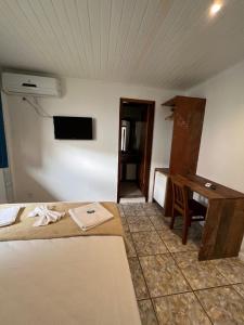 um quarto com uma cama, uma secretária e uma mesa em Tortuguita Ossos - Suítes em Búzios