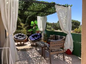une terrasse avec des chaises et une pergola avec des rideaux dans l'établissement B&B Macchia Verdata avec piscine, à Monacia-dʼAullène