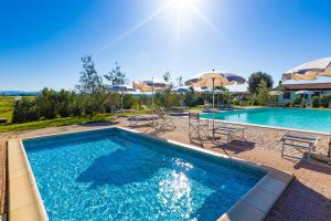 a swimming pool with umbrellas and chairs and a pool at Agriturismo Gli Etruschi in Populonia