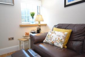 a brown leather couch in a living room with a lamp at Unique restored Old Post Office in Kinlochleven