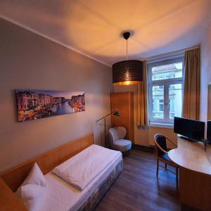 Schlafzimmer mit einem Bett, einem Schreibtisch und einem Tisch in der Unterkunft Hotel Friedensbruecke in Greiz