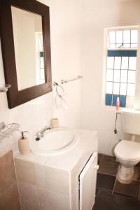 a white bathroom with a sink and a toilet at Lovely 1-bedroom flat in Germiston in Germiston