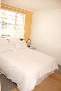 a white bed in a room with a window at Lovely 1-bedroom flat in Germiston in Germiston