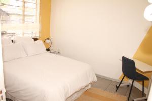 Schlafzimmer mit einem weißen Bett und einem Schreibtisch in der Unterkunft Lovely 1-bedroom flat in Germiston in Germiston