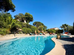 a swimming pool in a resort with chairs and trees at Le Mas du Soleil in Sainte-Maxime