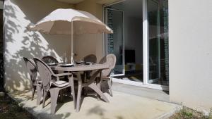 uma mesa e cadeiras com um guarda-sol num pátio em Appartement 2 pièces avec jardin privatif em Saint-André-de-Cubzac