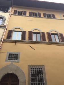 a yellow building with brown shuttered windows at Hand decorated house with court in Florence