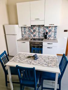 eine Küche mit einem Tisch mit blauen Stühlen und weißen Schränken in der Unterkunft La Finestra su Spello in Spello
