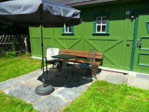 einem Picknicktisch und einem Regenschirm vor einem grünen Gebäude in der Unterkunft Tiny House in Thermalbad Wiesenbad