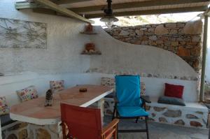 Habitación con mesa, sillas y pared de piedra. en COSY STUDIO IN ALLOPRONOIA SIKINOS en Alopronia