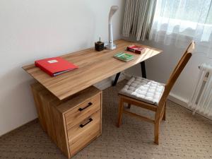 バーデン・バーデンにあるFerienwohnung am Krippenhofの木製デスク(椅子、赤い本付)
