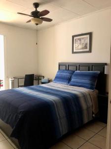 a bedroom with a blue bed with a ceiling fan at Room near Airport/ Cerca del Aeropuerto in Santiago Este