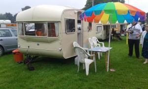 einen Tisch mit einem Regenschirm neben einem Wohnwagen in der Unterkunft Retro Caravan with Mountain Views in Abergavenny