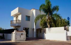 une maison blanche avec un palmier en face dans l'établissement 2-bedroom Villa with private pool in Anarita Paphos, à Anarita
