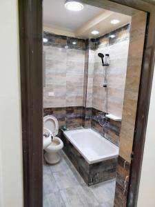 a bathroom with a bath tub and a toilet at شقه 115متر سوبر لوكس العامريه قريبه من الاسكندريه10min from Alexanderia in ‘Izbat al Musta‘marah