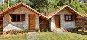 a small stone house with a wooden door at Pousada Duplátanos in Monte Verde