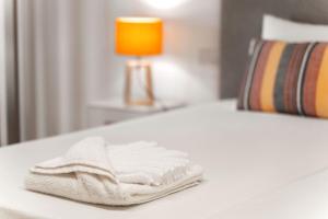 a white towel sitting on a bed with a lamp at Quinta das Andorinhas in Carvoeiro