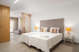 a bedroom with a large white bed and a chair at Quinta das Andorinhas in Carvoeiro