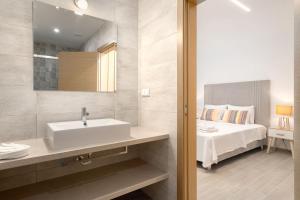 a white bathroom with a sink and a bed at Quinta das Andorinhas in Carvoeiro