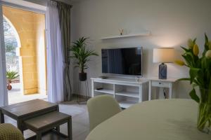 a living room with a television on a white table at Luzzu - Family Friendly Maisonette in Xlendi