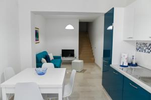 cocina y sala de estar con mesa blanca y armarios azules en Casetta Primo Sole Apartments, en Policoro