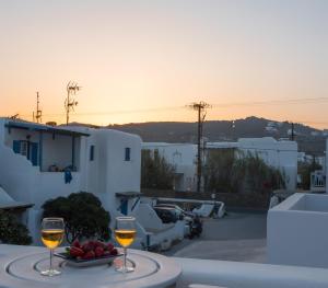 a table with two glasses of wine and a bowl of fruit at Escape to Mykonos - Entire place by Ornos beach in Ornos