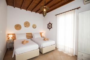 two beds in a bedroom with white walls and a window at Escape to Mykonos - Entire place by Ornos beach in Ornos