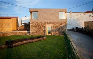 une maison en briques avec une cour d'herbe devant elle dans l'établissement Casas de Vale de Lobo, à Mirandela