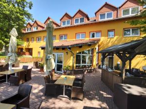 ein Restaurant mit Tischen und Sonnenschirmen vor einem Gebäude in der Unterkunft Hotel-Restaurant Weinberg in Artern