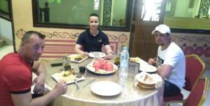 Un gruppo di uomini seduti a tavola che mangiano cibo di Hôtel Sable d'Or a Tan-Tan
