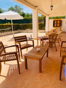 a patio with wooden chairs and tables and an umbrella at Quinta das Andorinhas in Carvoeiro