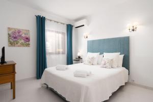 a bedroom with a large white bed with blue curtains at Quinta das Andorinhas in Carvoeiro