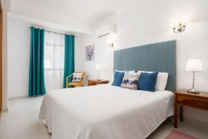 a bedroom with a large bed with blue curtains at Quinta das Andorinhas in Carvoeiro