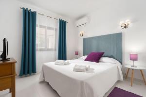 a bedroom with a large white bed with purple accents at Quinta das Andorinhas in Carvoeiro