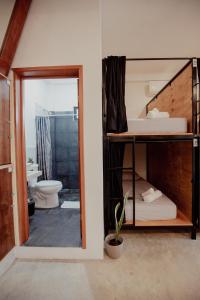 a room with bunk beds and a bathroom with a toilet at Hostal Del Jaguar in Tulum