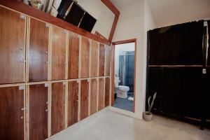 a bathroom with wooden doors and a toilet at Hostal Del Jaguar in Tulum
