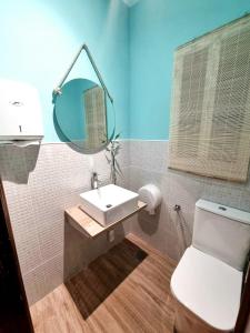 een badkamer met een wastafel, een toilet en een spiegel bij Pension Angelines, Sneuu Hostel Santander in Santander