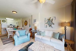 sala de estar con sofá blanco y silla azul en Tradewind 1204, en Orange Beach