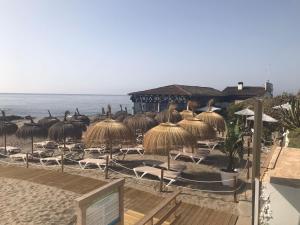 ミハス・コスタにあるMalaga Mijas Costa Pool Nuevo Pisoの海の景色を望むビーチ(椅子、わらパラソル付)